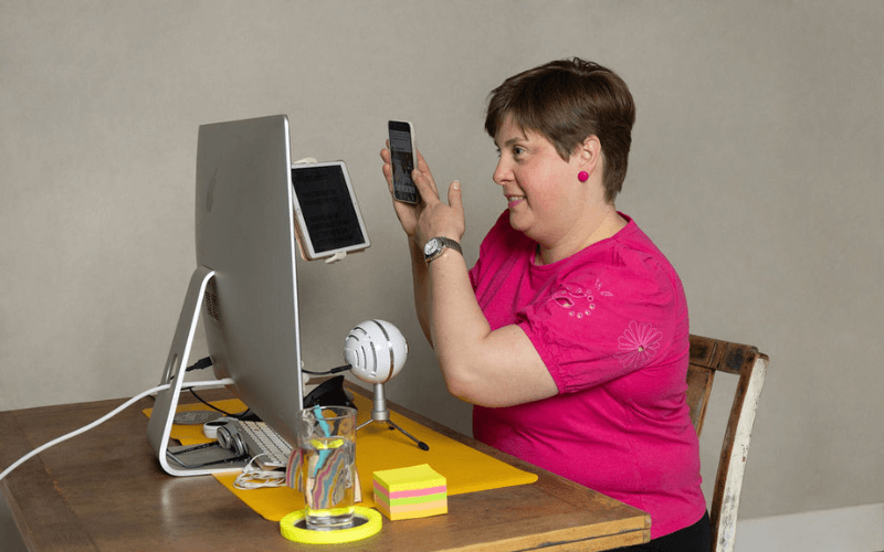 Lou, sat at a desk looking through a magnifying eyepiece to read something on a notepad close to her face